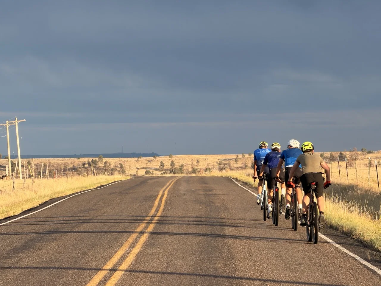 A group of cyclists riding an open Montana road under a wide sky