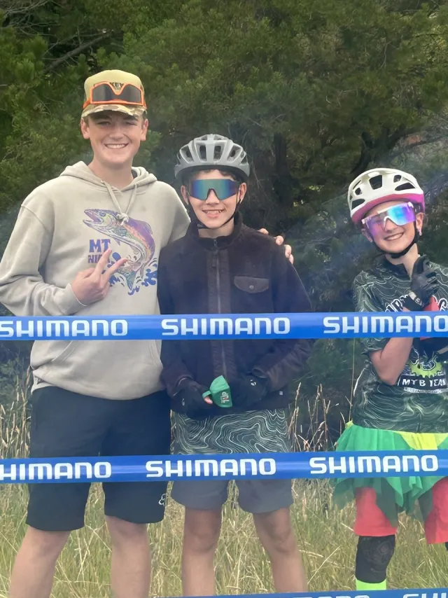Three teammates smiling together beside the course